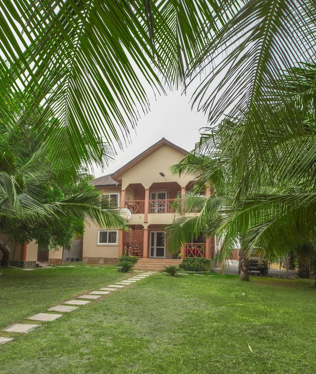 A family house with a garden path and palm trees in Prampram, Ghana