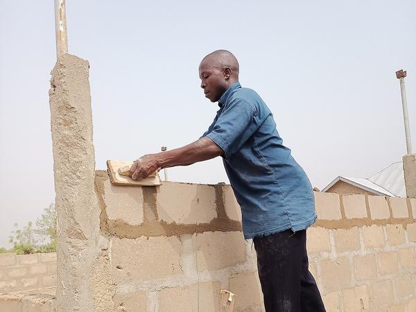 A mason building a block wall in Northern Ghana